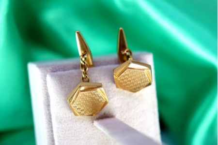  Botões de punho em ouro guilhochados em forma de hexágono.